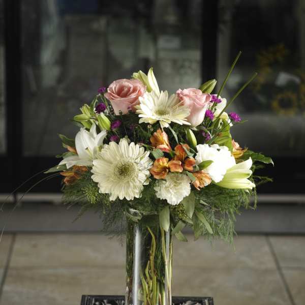 Mixed pink and white flowers arranged in a clear glass vase