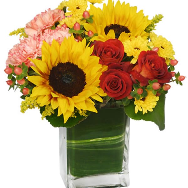 Bouquet of sunflowers, red roses, and pink carnations in a glass vase