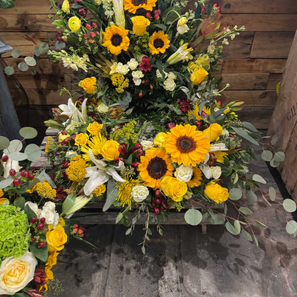 Large yellow and white floral arrangement with sunflowers and roses
