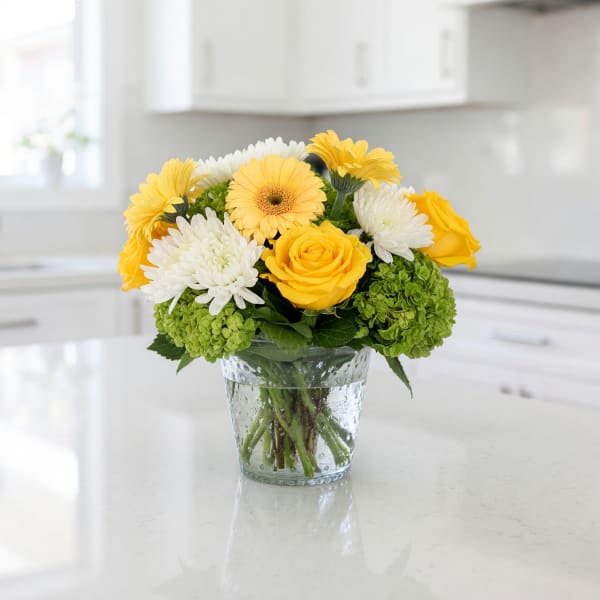 Yellow and white flowers arranged in a clear glass vase