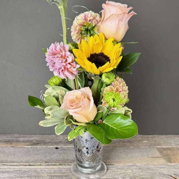 Mixed bouquet with sunflowers, pale pink roses, and chrysanthemums in a glass vase