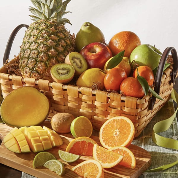 Basket of assorted fruit with sliced citrus and mango on a cutting board
