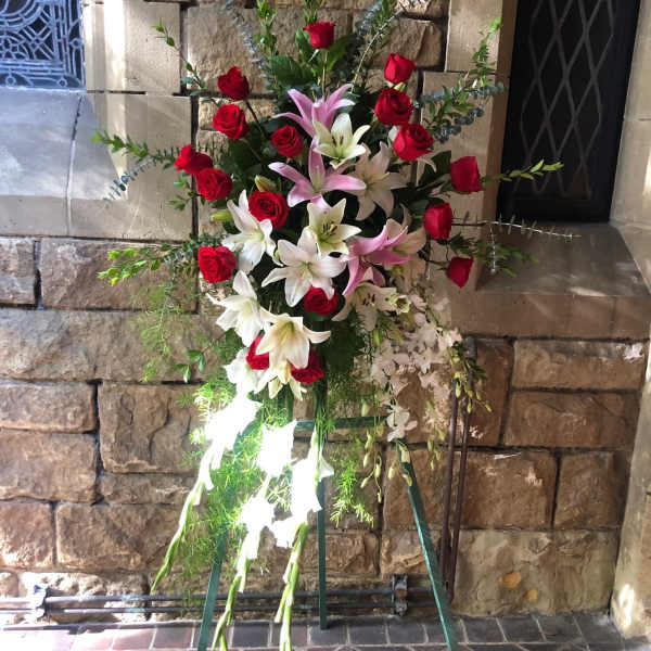Standing floral spray with red roses and white lilies on a metal easel
