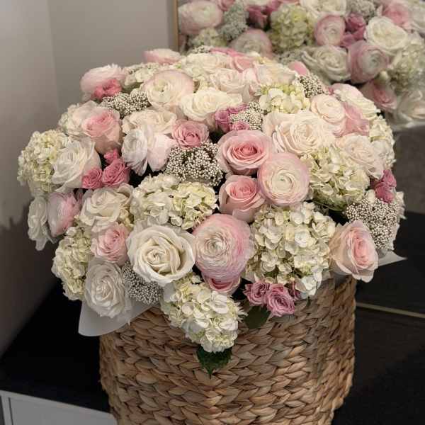 Large pink and white rose arrangement in a woven basket