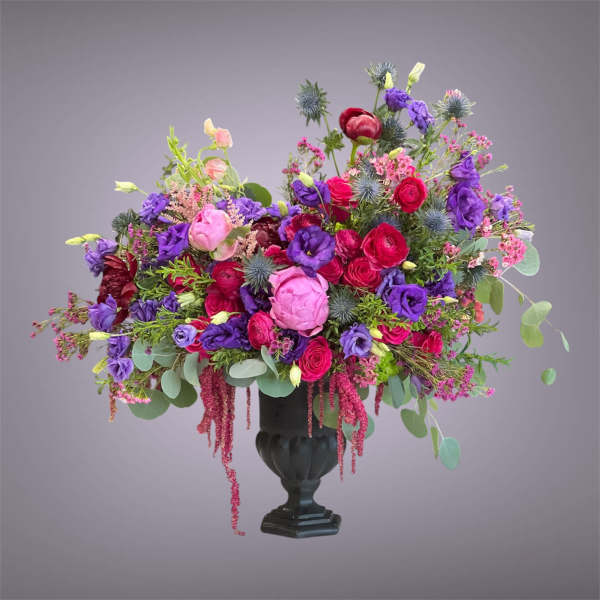 Colorful bouquet of pink, red, and purple flowers in a black urn vase