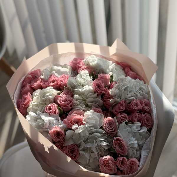 Bouquet of pink roses and white hydrangeas wrapped in pale pink paper