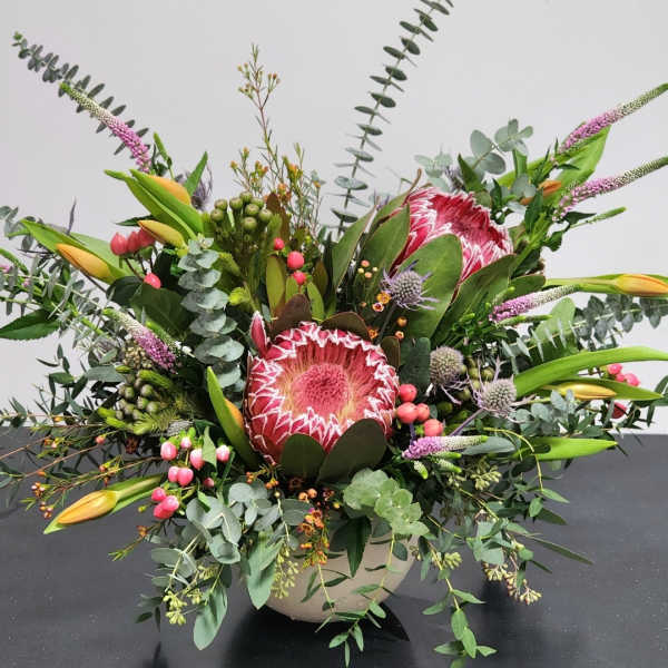 Large mixed bouquet with pink protea and yellow lilies in a vase