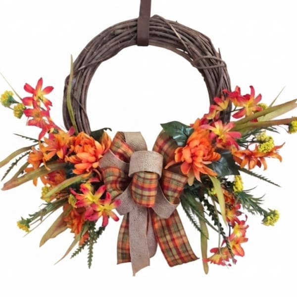 Fall wreath with orange flowers and a plaid bow on a grapevine ring