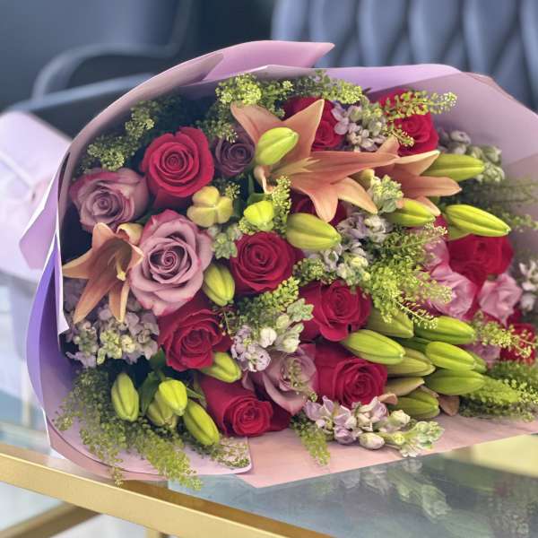Bouquet of red and lavender roses with peach lilies