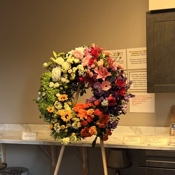 Large circular floral wreath on an easel with mixed roses and lilies