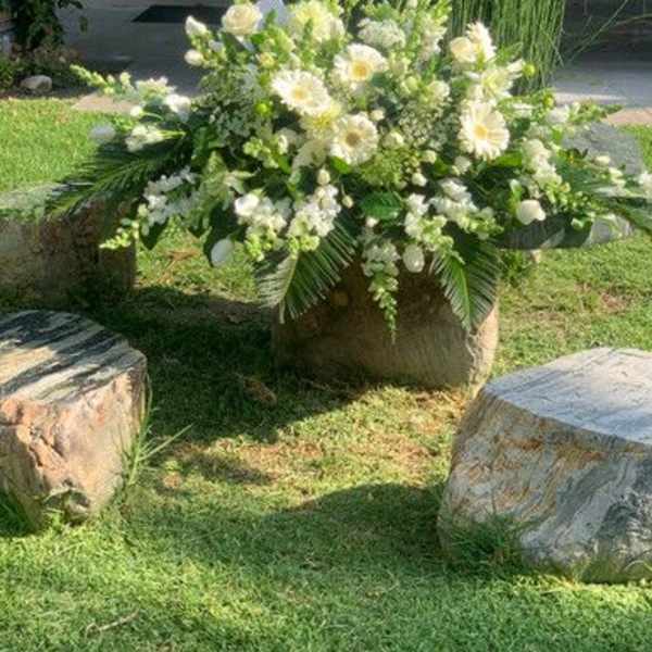 Large white floral arrangement in a stone container outdoors
