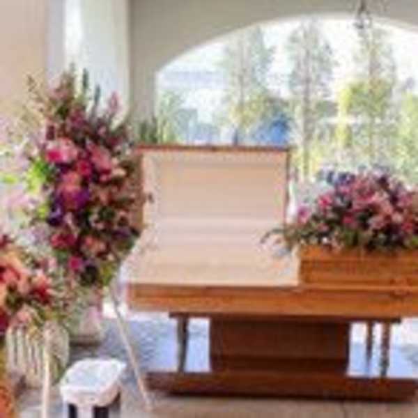 Casket surrounded by large pink and purple floral sprays