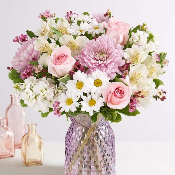 Pink and white mixed bouquet in a purple glass vase