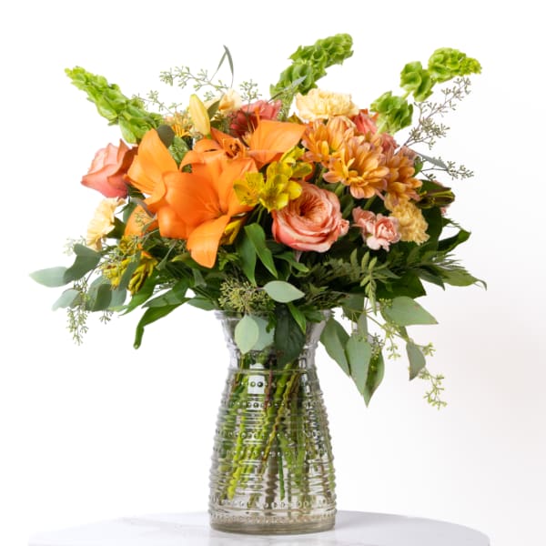 Orange and peach mixed flower bouquet in a clear glass vase
