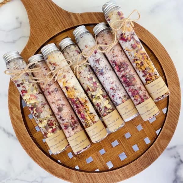 Set of floral bath salt tubes tied with twine on a wooden tray