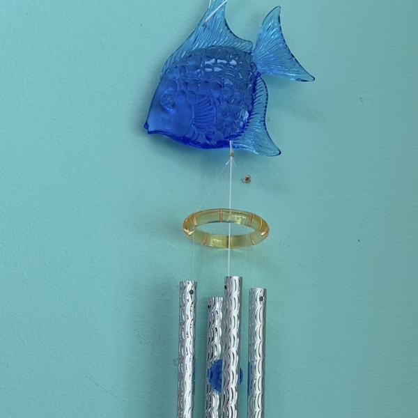 Hanging wind chime with blue fish, silver tubes, and blue crystal drop on a teal wall