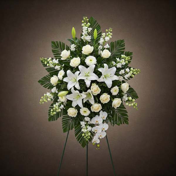 White floral standing spray with lilies and roses on an easel