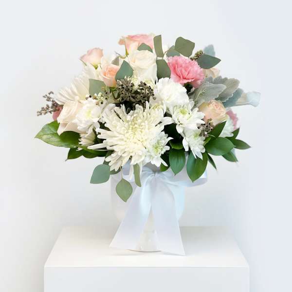 Bouquet of white and blush flowers in a white vase with a ribbon