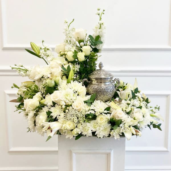 White floral arrangement with roses, lilies, and chrysanthemums in a silver urn