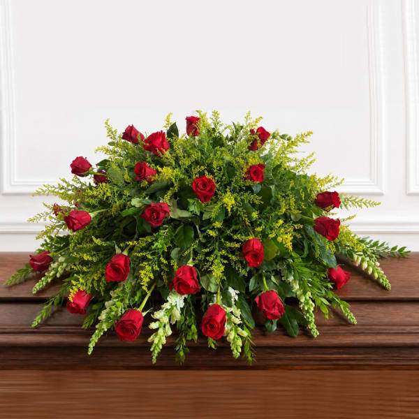 Red roses arranged in a low, full centerpiece with mixed greenery