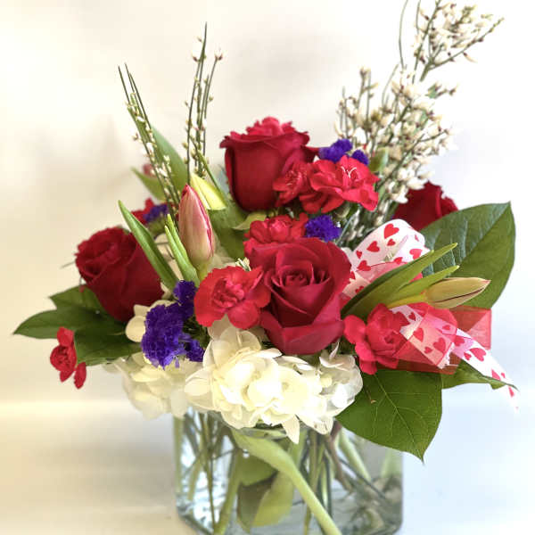 Red roses and mixed flowers in a square glass vase with heart ribbon