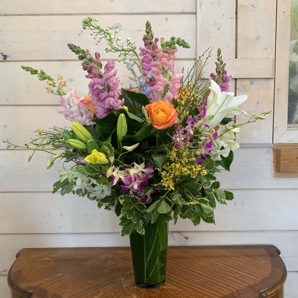 Mixed bouquet with roses, lilies, and snapdragons in a green vase