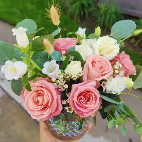 Pink and white rose bouquet in a glass vase with eucalyptus and small white blooms