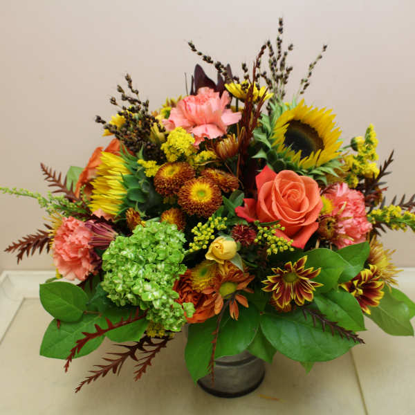 Mixed bouquet with sunflowers, roses, carnations, and chrysanthemums in a metal vase