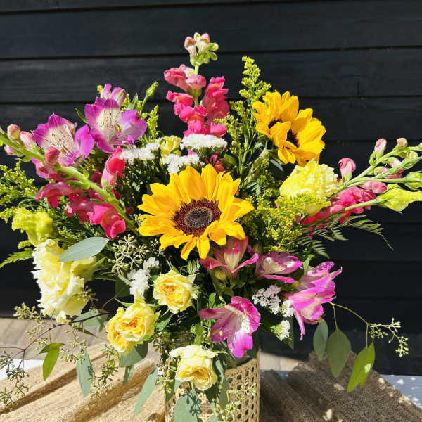 Mixed bouquet with sunflowers, pink alstroemeria, and yellow roses in a decorative vase