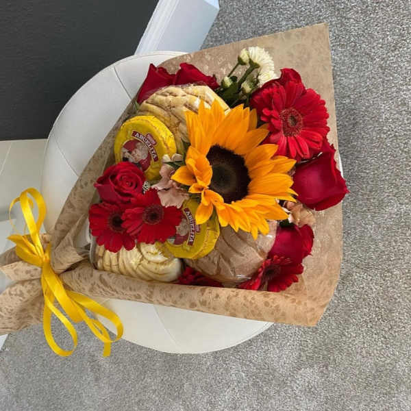Bouquet of red roses and sunflowers with packaged bread and a yellow ribbon