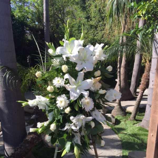 White funeral spray on an easel with lilies and daisies
