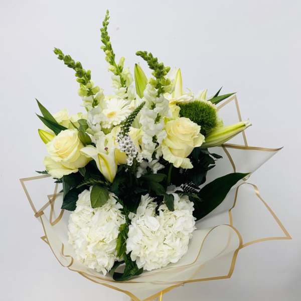 Bouquet of white and pale yellow flowers wrapped in clear paper with gold trim