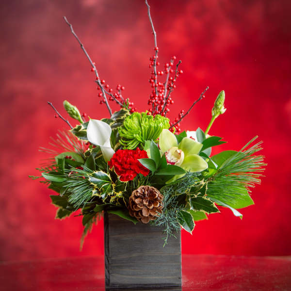Holiday floral arrangement in a dark square vase with red, white, and green blooms