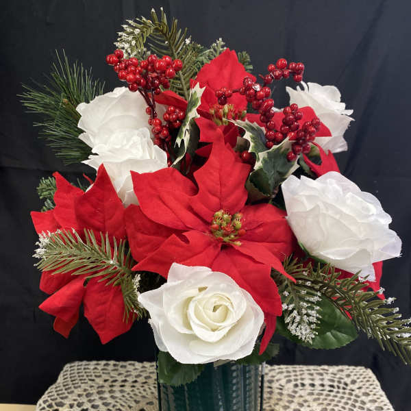 Red and white floral arrangement in a green vase with pine accents