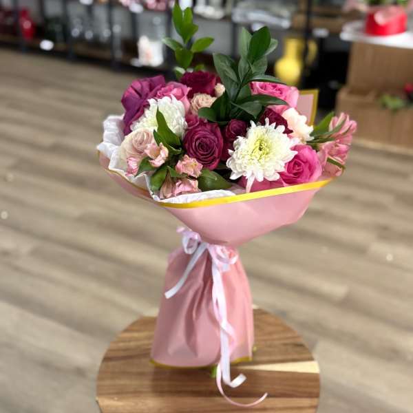 Pink and white bouquet of roses and chrysanthemums wrapped in pink paper