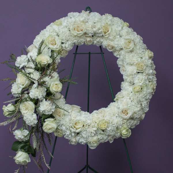 White floral funeral wreath on a green stand