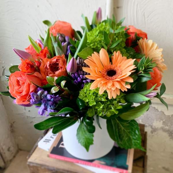 Bouquet of orange and purple flowers in a white vase