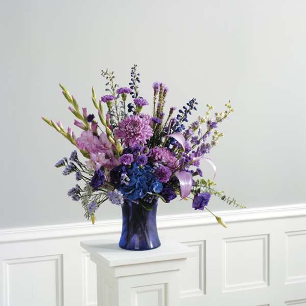 Purple and blue floral arrangement in a dark blue vase