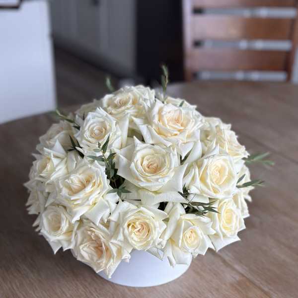 Round bouquet of cream white roses in a white container