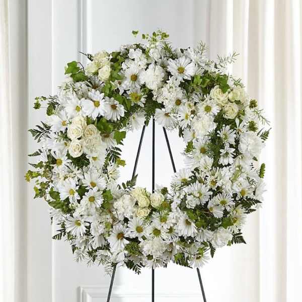 White floral wreath on a black stand