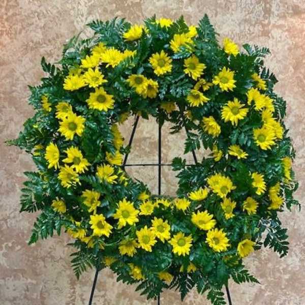 Yellow daisy wreath on a black stand