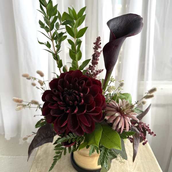 Dark burgundy floral arrangement with a black calla lily in a vase