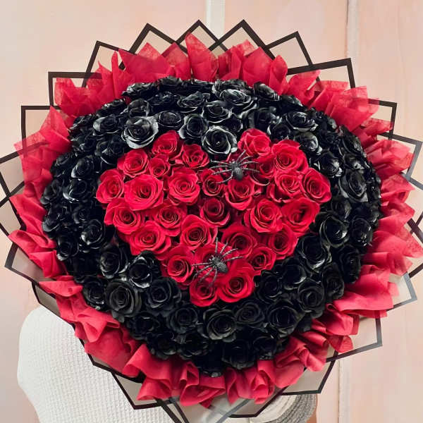 Heart-shaped bouquet of red and black roses with red tissue wrap