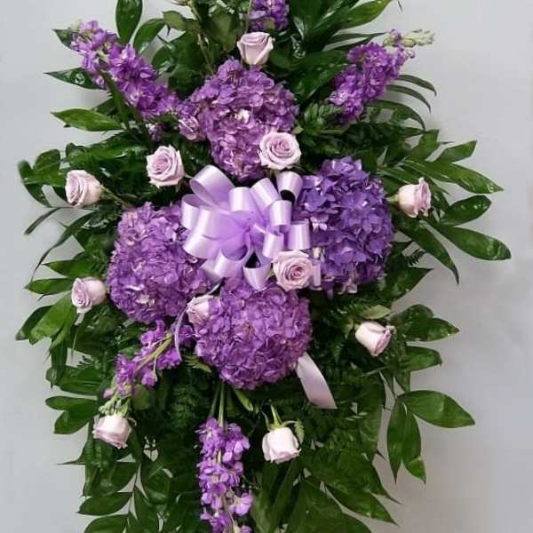 Purple floral standing spray with roses and hydrangeas on a ribboned easel
