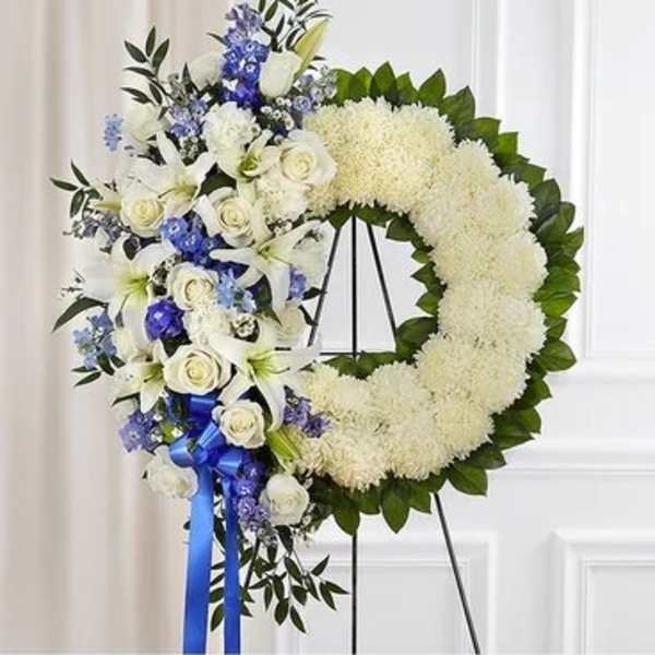 White and blue funeral wreath with roses and lilies on an easel