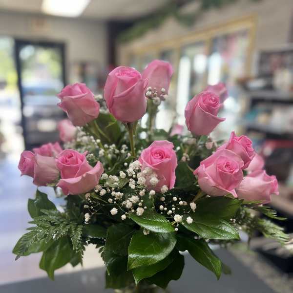 Pink roses arranged in a clear glass vase with baby's breath