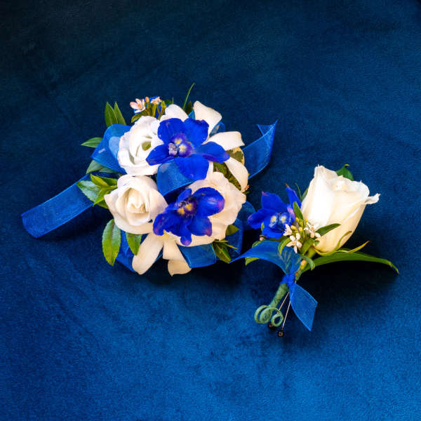 White and blue floral boutonniere and wrist corsage on blue fabric