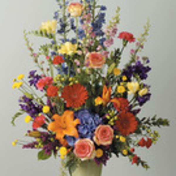 Tall mixed flower arrangement in a vase with bright multicolored blooms