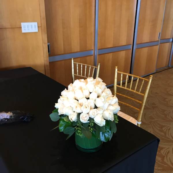 White rose arrangement in a green vase on a black table