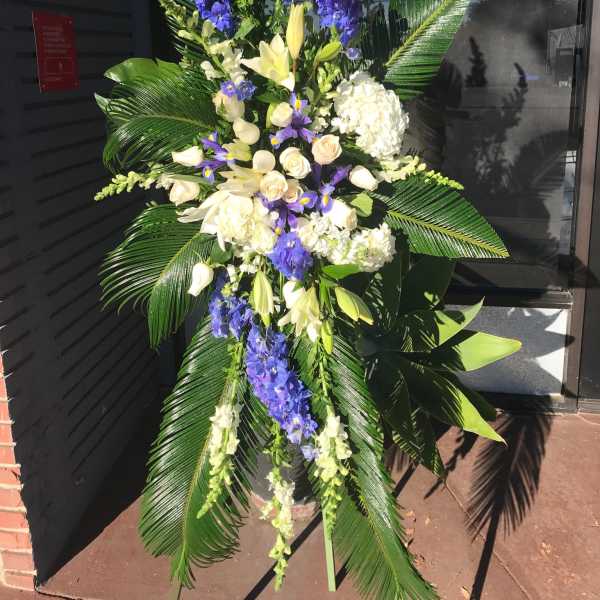 Tall standing floral spray with white and purple flowers and large palm leaves